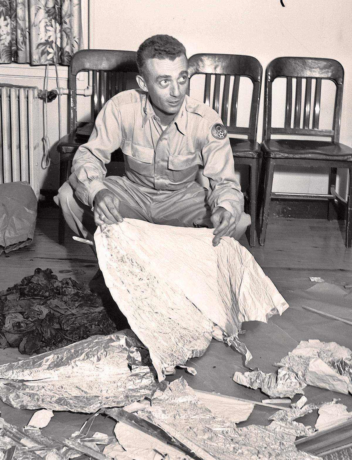 Major Jesse A. Marcel (looking right) of Houma, Louisiana, holding foil debris from Roswell, New Mexico UFO crash site, July 1947.
