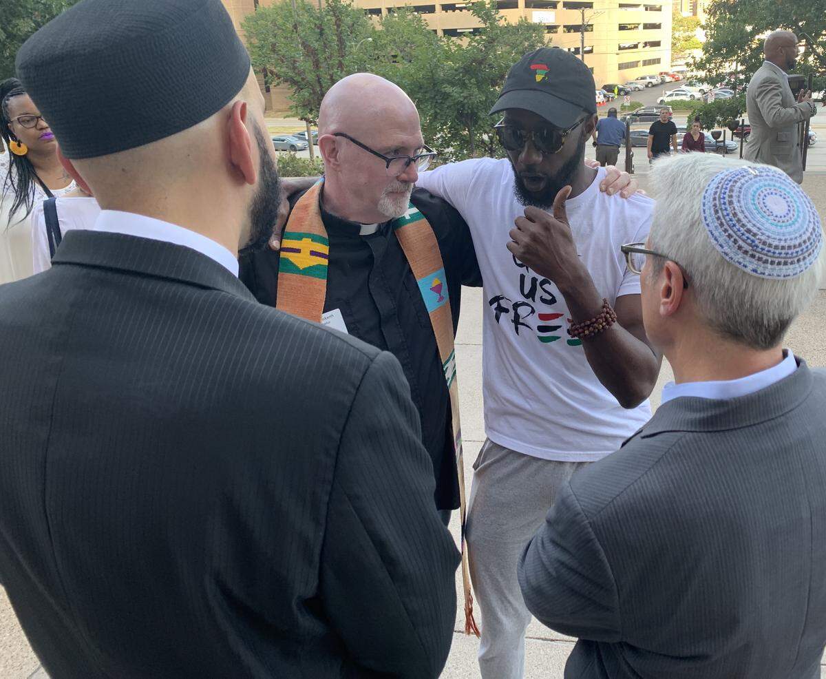 The Rev. Eric Folkerth of Kessler Park United Methodist Church (upper left), community organizer the Rev. Edwin Robinson, Rabbi David Stern of Temple Emanu-El and Imam Omar Suleiman of Yaqeen Institute of Islamic Research share fellowship Tuesday evening outside the Frank Crowley Courts Building in Dallas.
