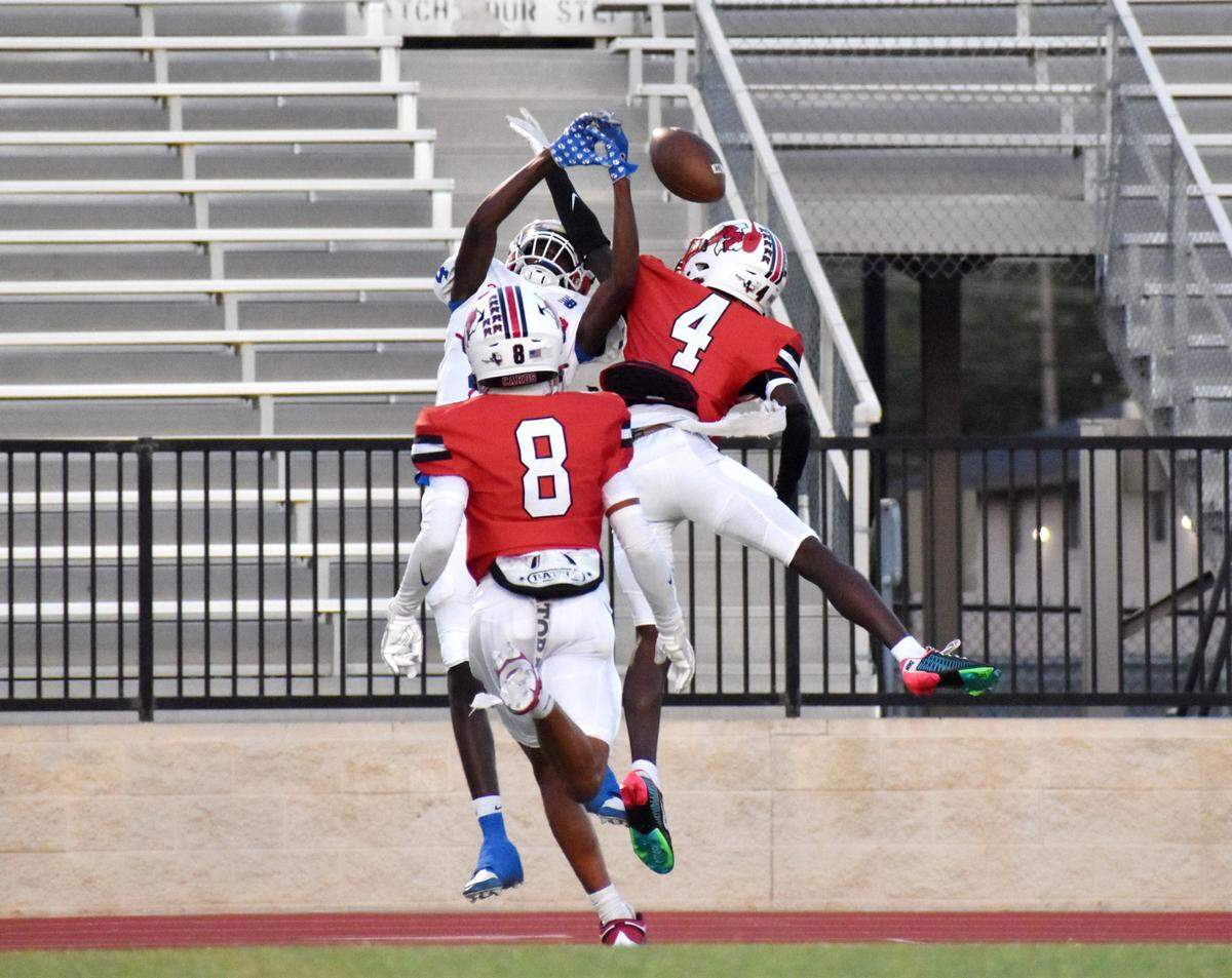Sam Houston wide receiver Jayden Philips jumps for a pass while being defended by Irving MacArthur’s La’Tron Roundtree (4) and Jayden Ngetich (8) during a game Thursday in Irving.