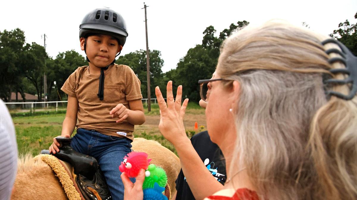 Program director Veronica Wolfe works with MJ Hernandez during an equestrian therapy session at All Star Equestrian Foundation in Burleson on May 23, 2024. Much of MJ’s care has been provided through a Medicaid health insurance program for children and teenagers with disabilities or other special health needs.