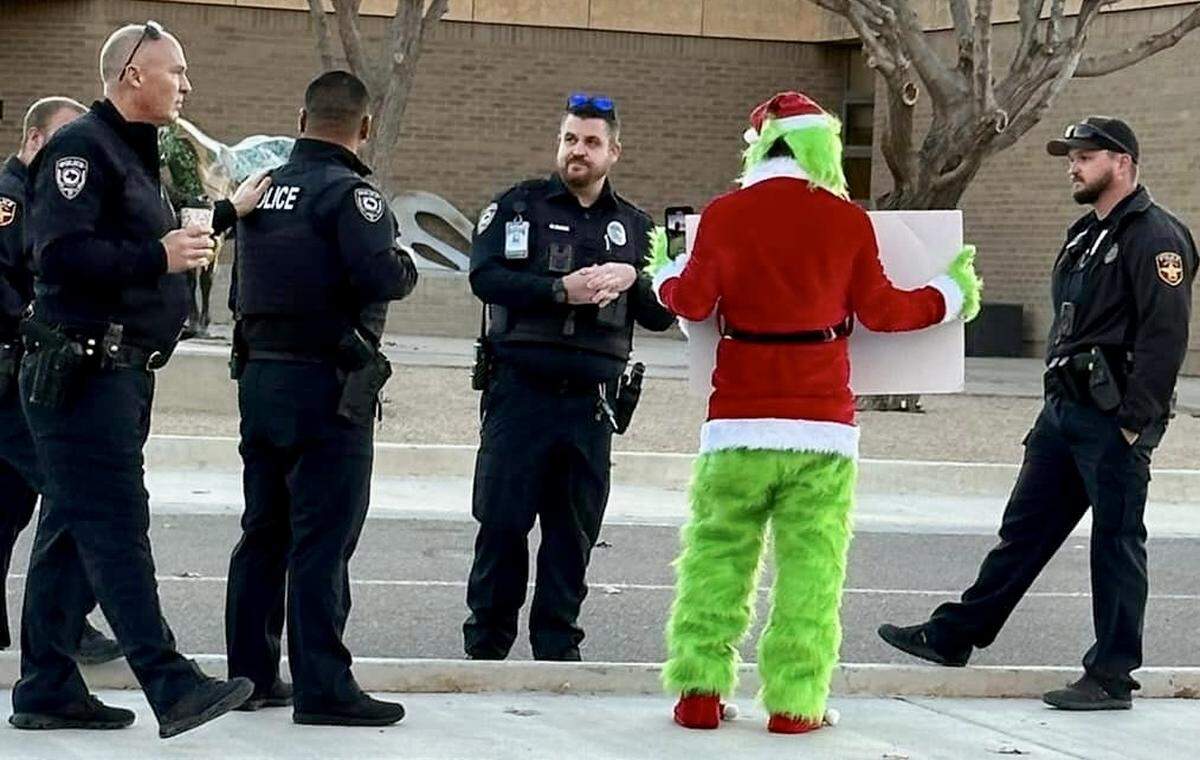 Amarillo police and school district officers responded to street preacher David Grisham’s anti-Santa protest dressed as “The Grinch” Nov. 27, 2023, at Sleepy Hollow Elementary School in Amarillo, Texas. Grisham’s sign read, “SANTA IS / FAKE / JESUS IS / REAL.”