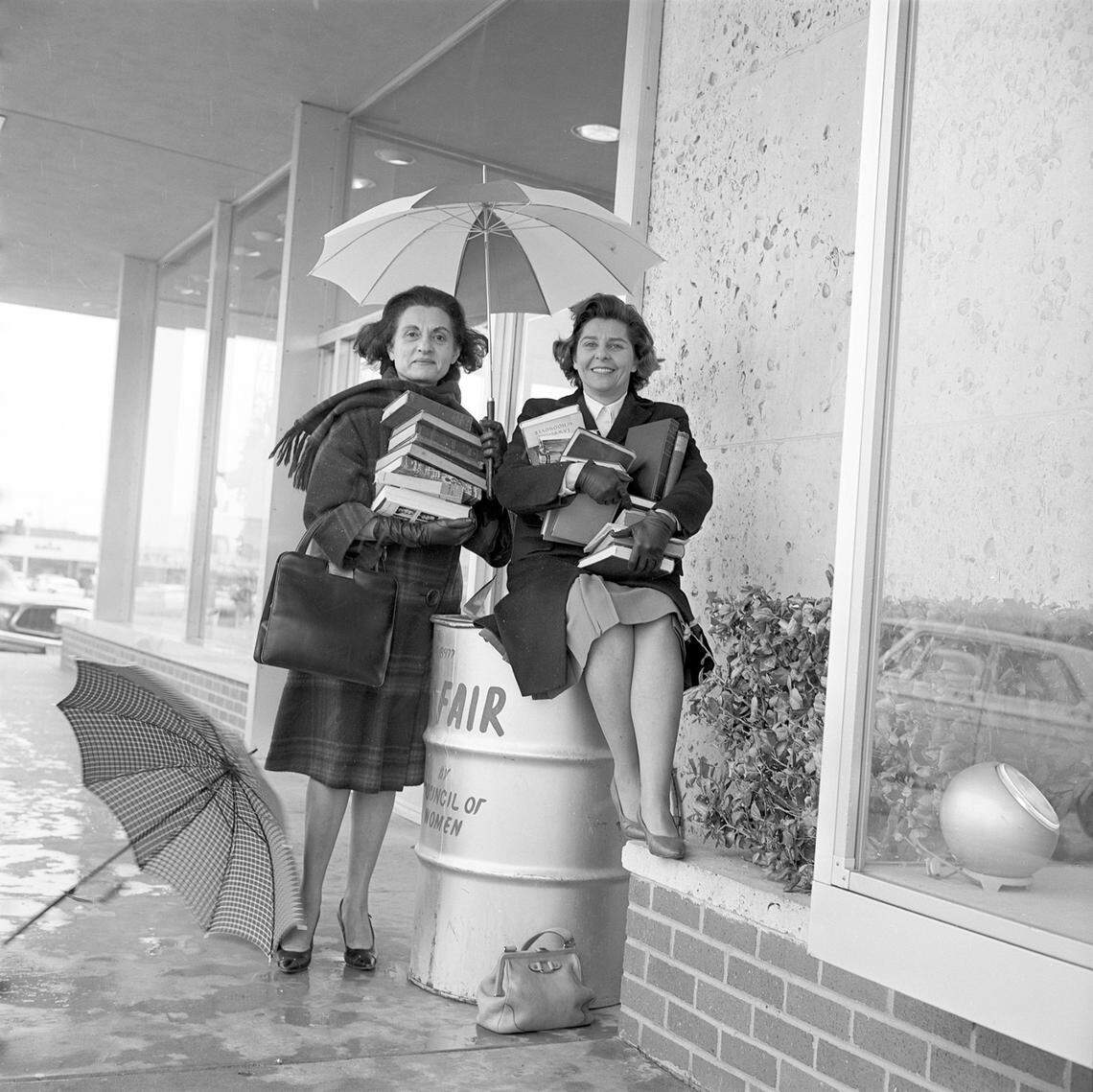 Florence Kohn, left, and Rozzy Rosenthal sit atop an oil drum, repurposed into a “book barrel,” where readers deposited used books and record albums sold at the annual National Council of Jewish Women Book Fair in 1964.