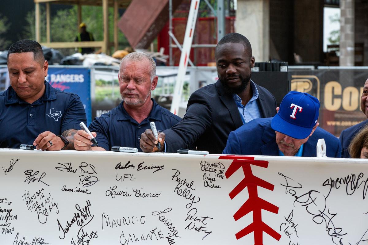 Executives and members from CBG building company sign the beam on Monday in Arlington’s entertainment district. City officials as well as building groups and construction crew were present at the event.