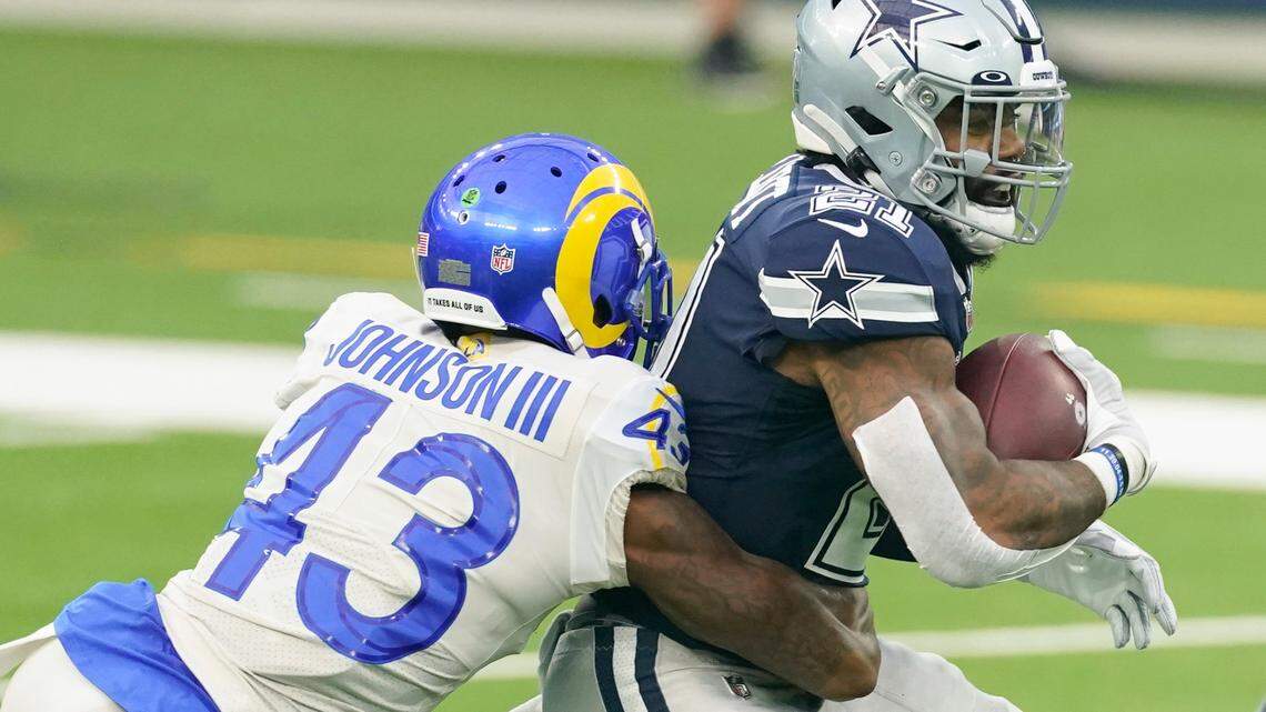 Dallas Cowboys running back Ezekiel Elliott, right, is tackled by Los Angeles Rams safety John Johnson III during Sunday’s game in Inglewood, Calif. (AP Photo/Ashley Landis )
