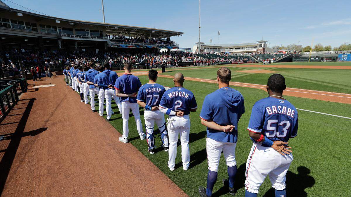 Texas Rangers players and coaches line-up along the first base side before a spring training baseball game against the Arizona Diamondbacks at Surprise Stadium Thursday, March 5, 2020, in Surprise, Ariz. (AP Photo/Elaine Thompson)
