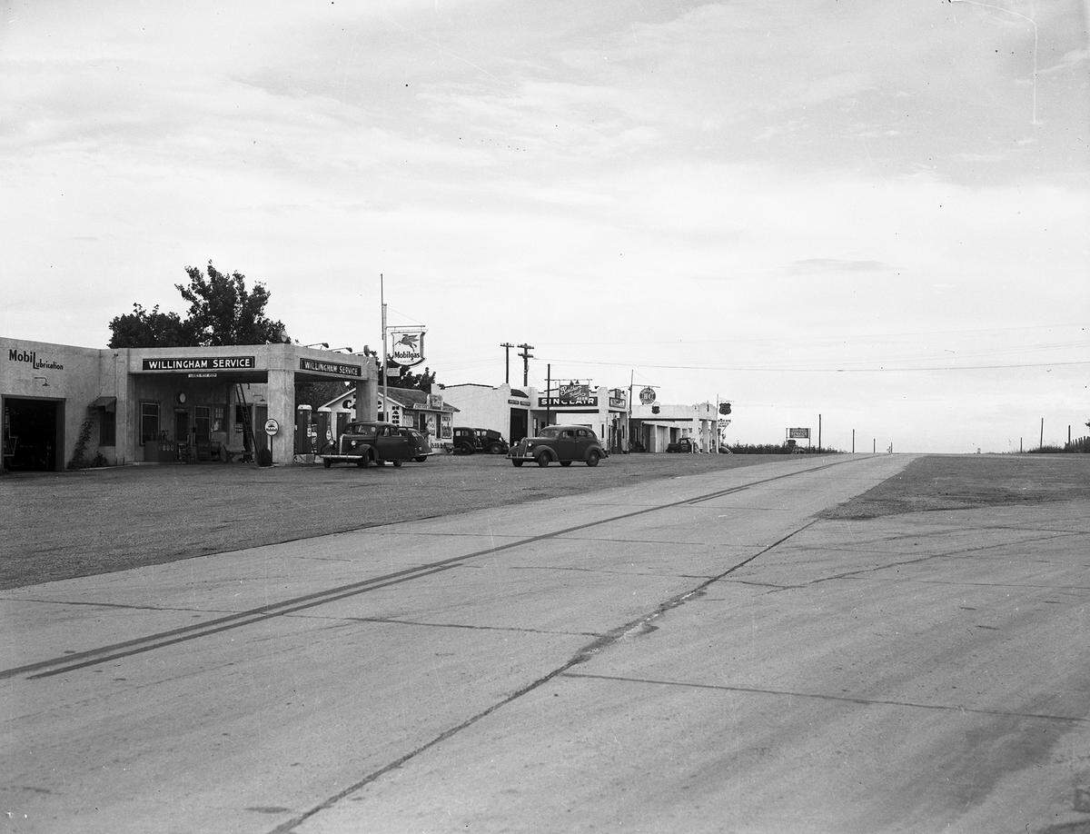 June 1940: The intersection of Highway 114 (Northwest Highway) and Highway 121 in Grapevine, Texas. On the side of the road, far left, are various buildings and businesses, including a Mobil gas station. A sign on the building reads “Willingham Service.” Another building has a sign out front advertising Southern Select Beer.