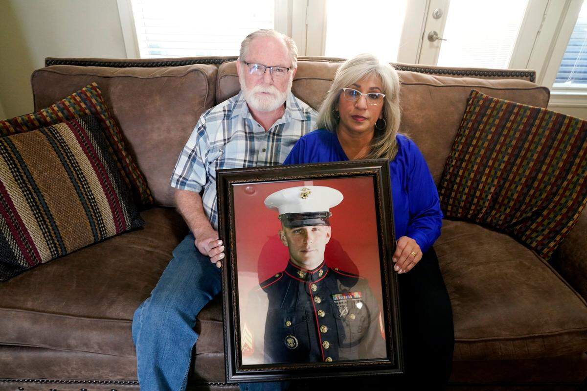 FILE - Joey and Paula Reed pose for a photo with a portrait of their son, Marine veteran and Russian prisoner Trevor Reed, at their home in Fort Worth, Texas, on Feb. 15, 2022. Russia is holding Trevor Reed, who was sentenced to nine years on charges he assaulted a police officer. The already-challenging path to bringing home Americans jailed in Russia and Ukraine is likely even more complicated now with a war overwhelming the region and increasingly hostile relations between the United States and the Kremlin. Marine veteran Trevor Reed and corporate security executive Paul Whelan are each serving long prison sentences in Russia.