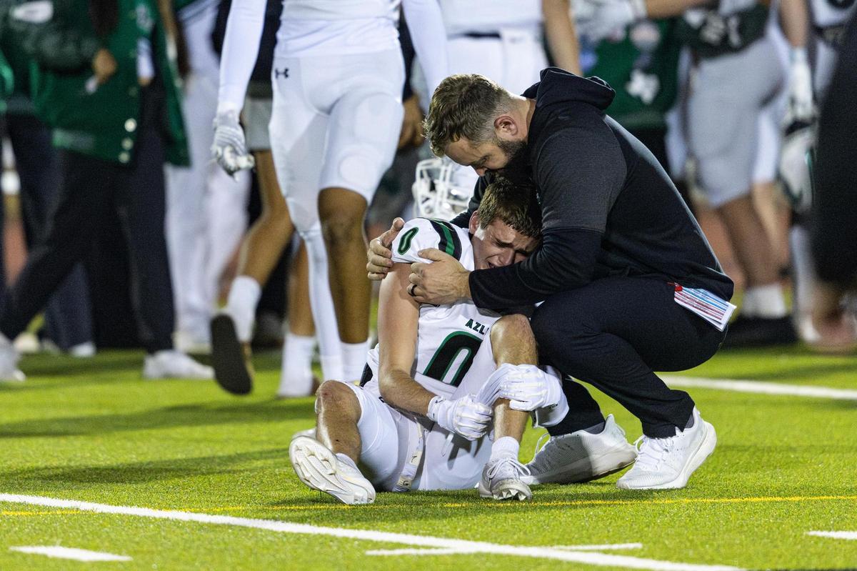 Azle defensive back Hunter Ooten (0) is consoled by an assistant coach after losing to Saginaw 41-39 in the Class 5A Division I playoffs game at Rough Rider Stadium in Saginaw on Friday, Nov. 15, 2024.