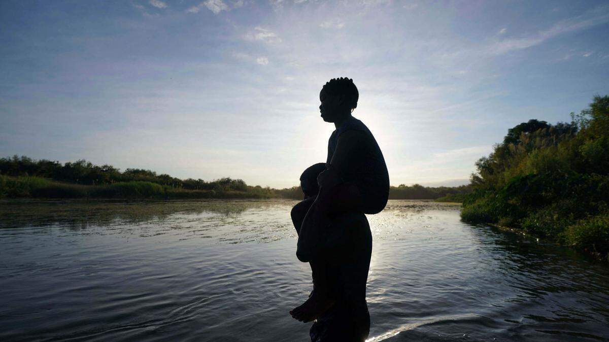 A father carries his daughter over the Rio Grande river toward Del Rio, Texas, from Ciudad Acuna, Mexico, Sept. 22, 2021. Two boys were swept away from their parents while trying to cross the river into America. The family is not pictured here.