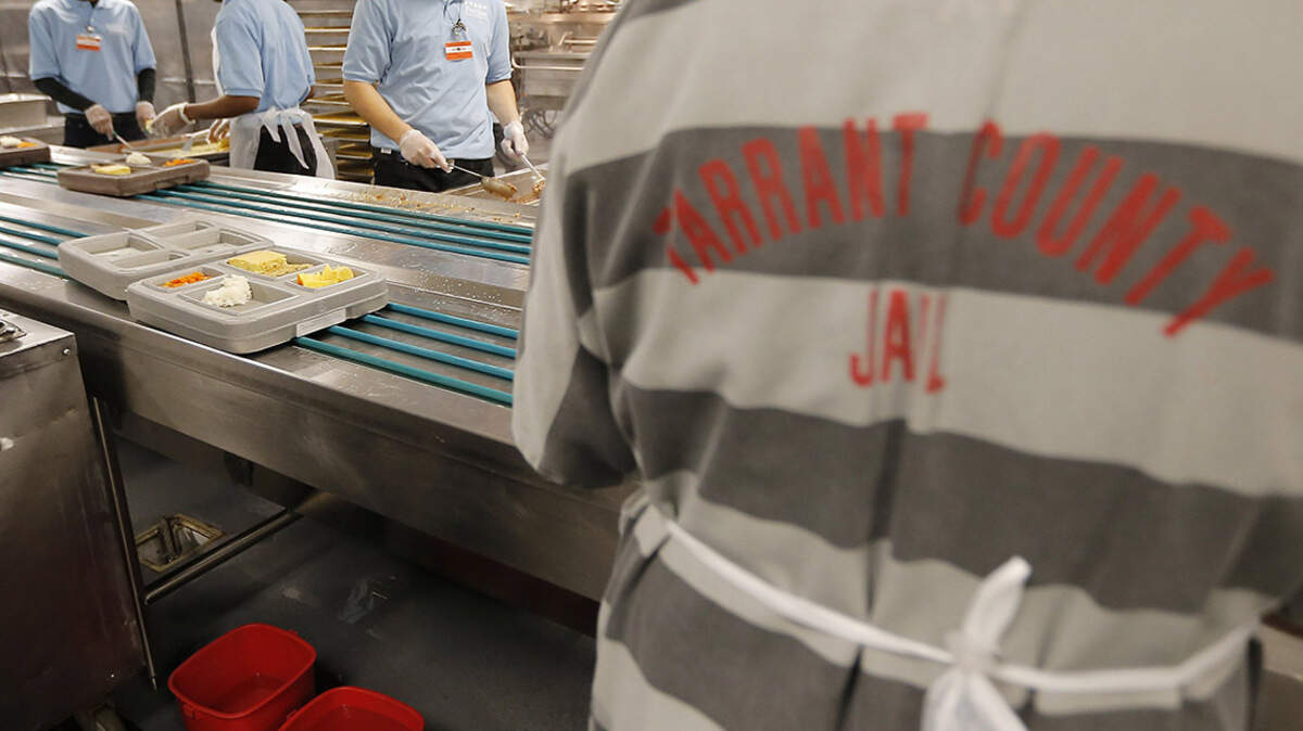 Five Star Correctional Services employees, in blue, prepare lunch trays as a Tarrant County Jail inmate stacks them for delivery at the Tarrant County Jail in downtown Fort Worth, Monday, November 23, 2015. Special/Brandon Wade