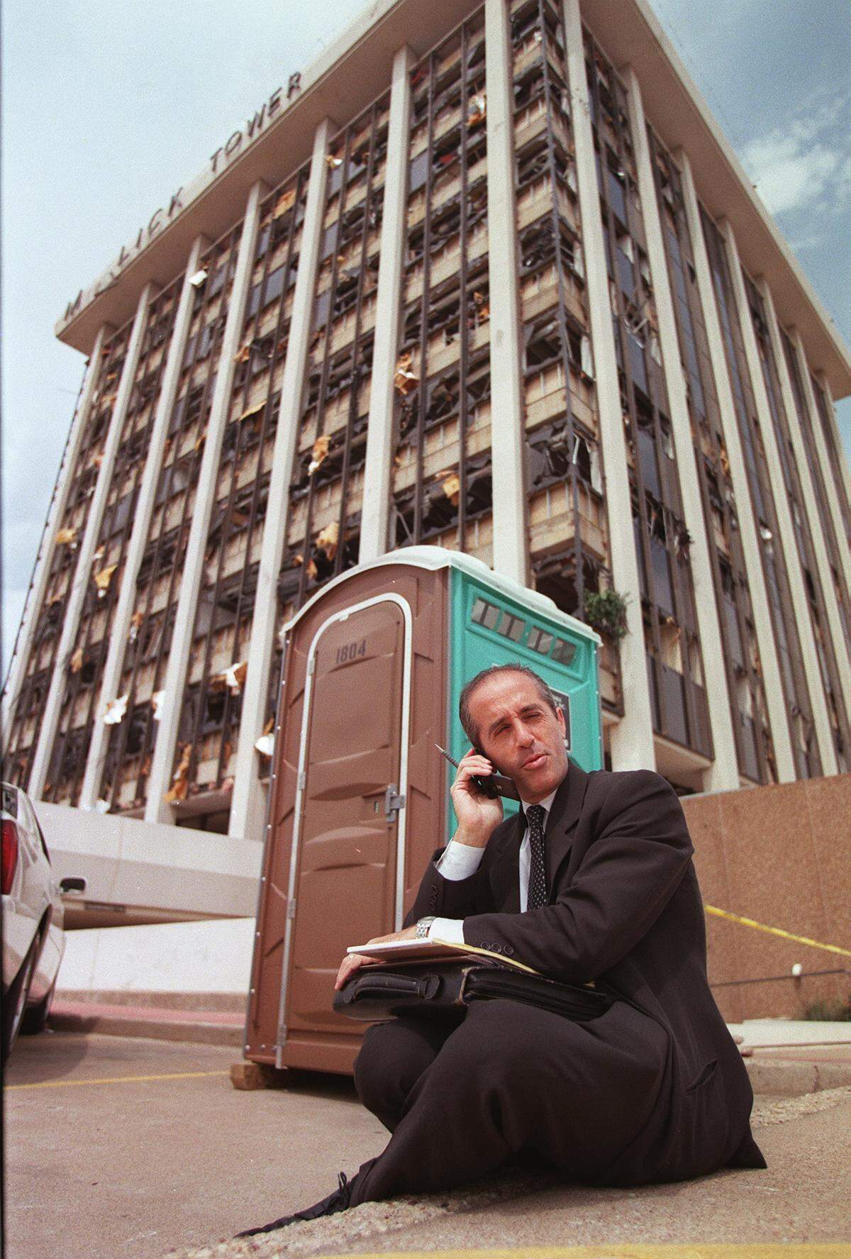 Stephen End {cq} regional manager with the Ritter Group (a loss managment firm) conducts business on the curb of Mallick Tower following the tornado that slammed into the building.