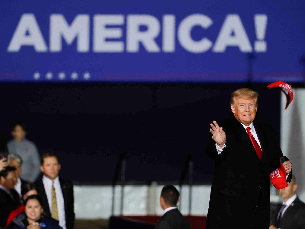 Former President Donald Trump throws hats into the crowd prior to speaking at a rally, Saturday, Jan. 29, 2022, in Conroe, Texas. (Jason Fochtman/Houston Chronicle via AP)