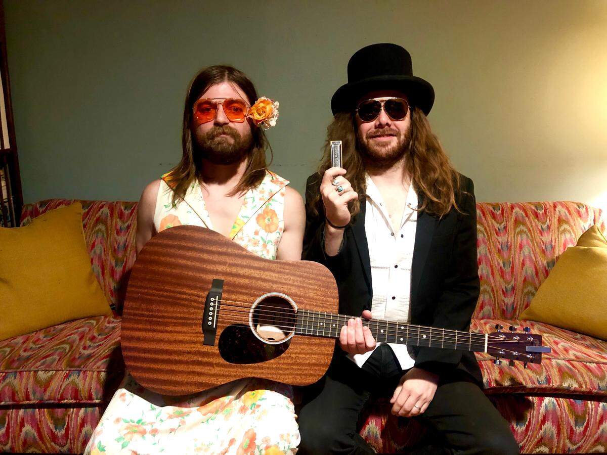 Blake Parish (right) and Kris Luther (left) pose for a photo before performing a concert from Parish’s living room for an audience on Facebook watching live. The bandmates haven’t been able to book gigs at venues amid the coronavirus pandemic.