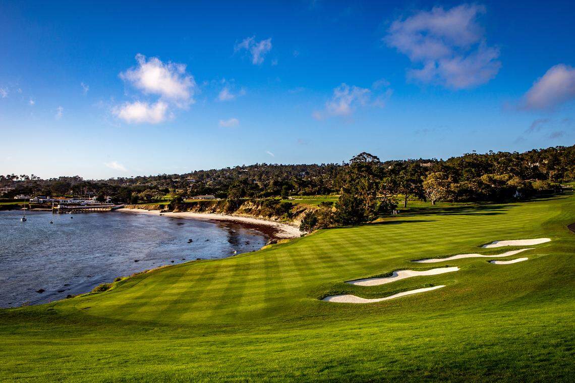 A green manicured golf course lawn sits next to the sandy beach coast of Monterey. 