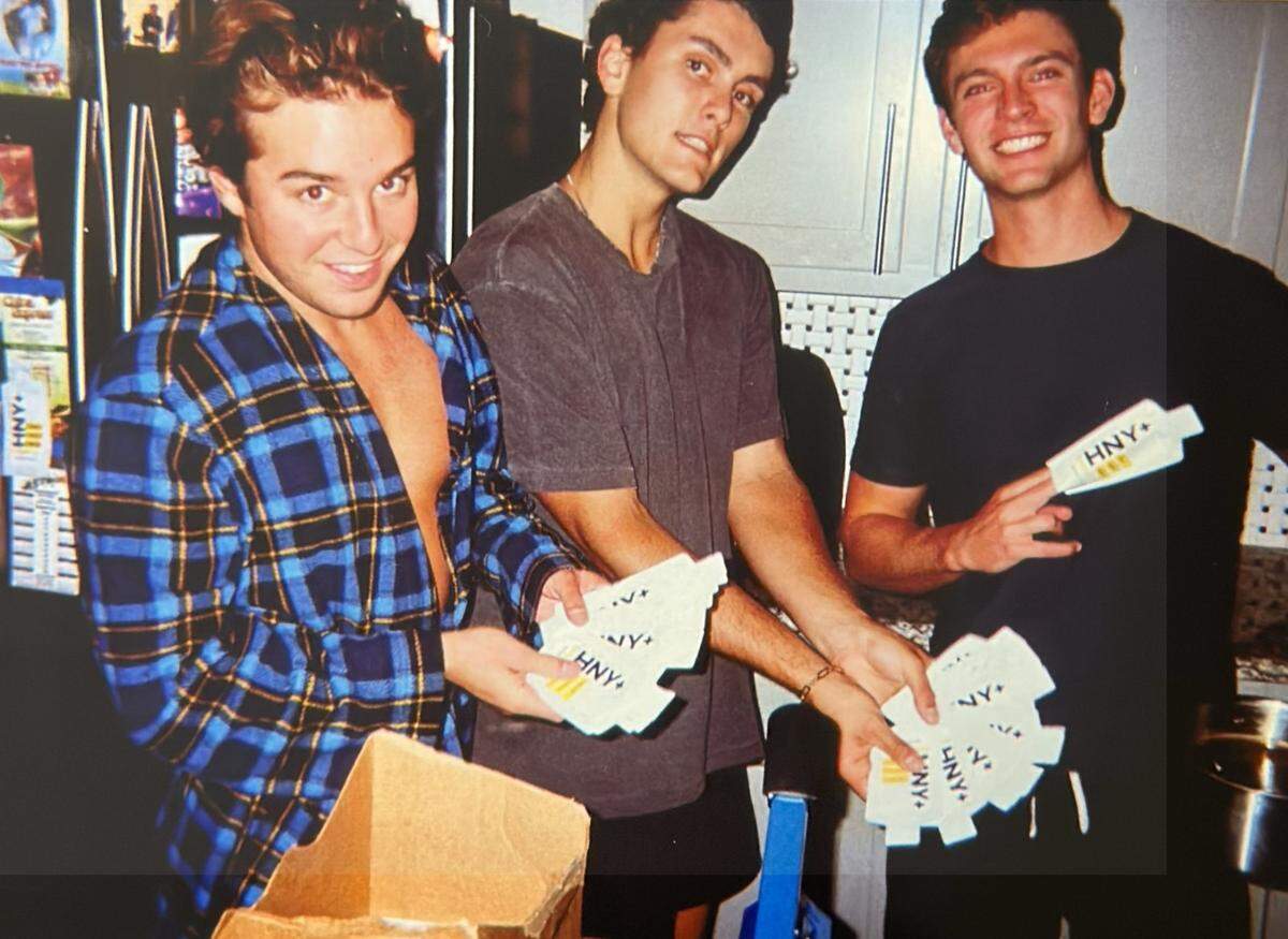 Luke Smialowicz (left), Liam Brogan (middle) and Ross Cooley (right) package up honey and salt into pouches at their Fort Worth college house to pass out to TCU students and athletes.