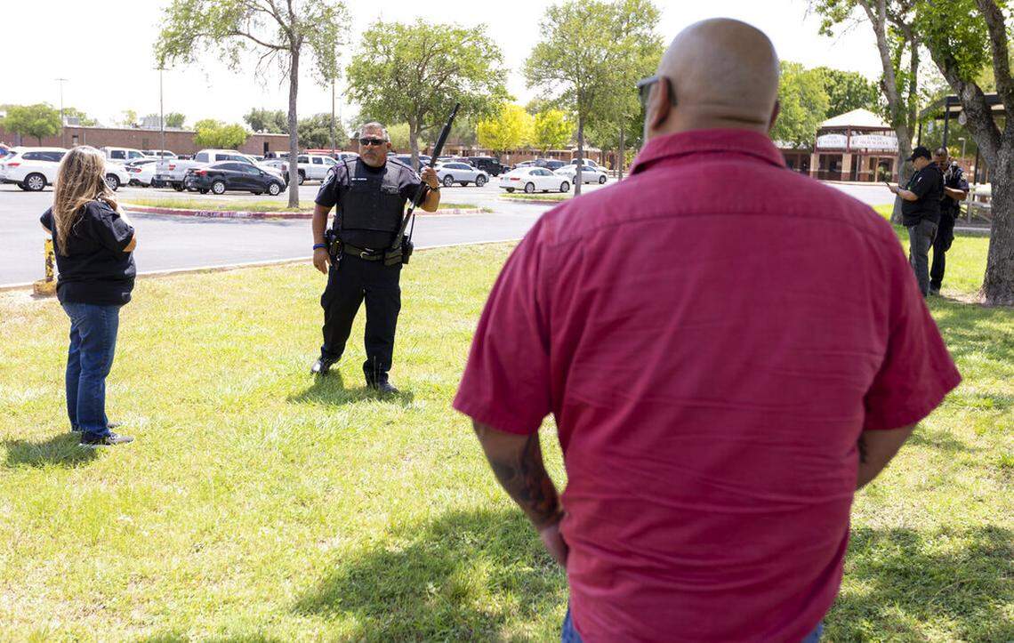 A law enforcement officer speaks with people outside Uvalde High School after shooting a was reported earlier in the day at Robb Elementary School, Tuesday, May 24, 2022, in Uvalde, Texas. (William Luther/The San Antonio Express-News via AP)