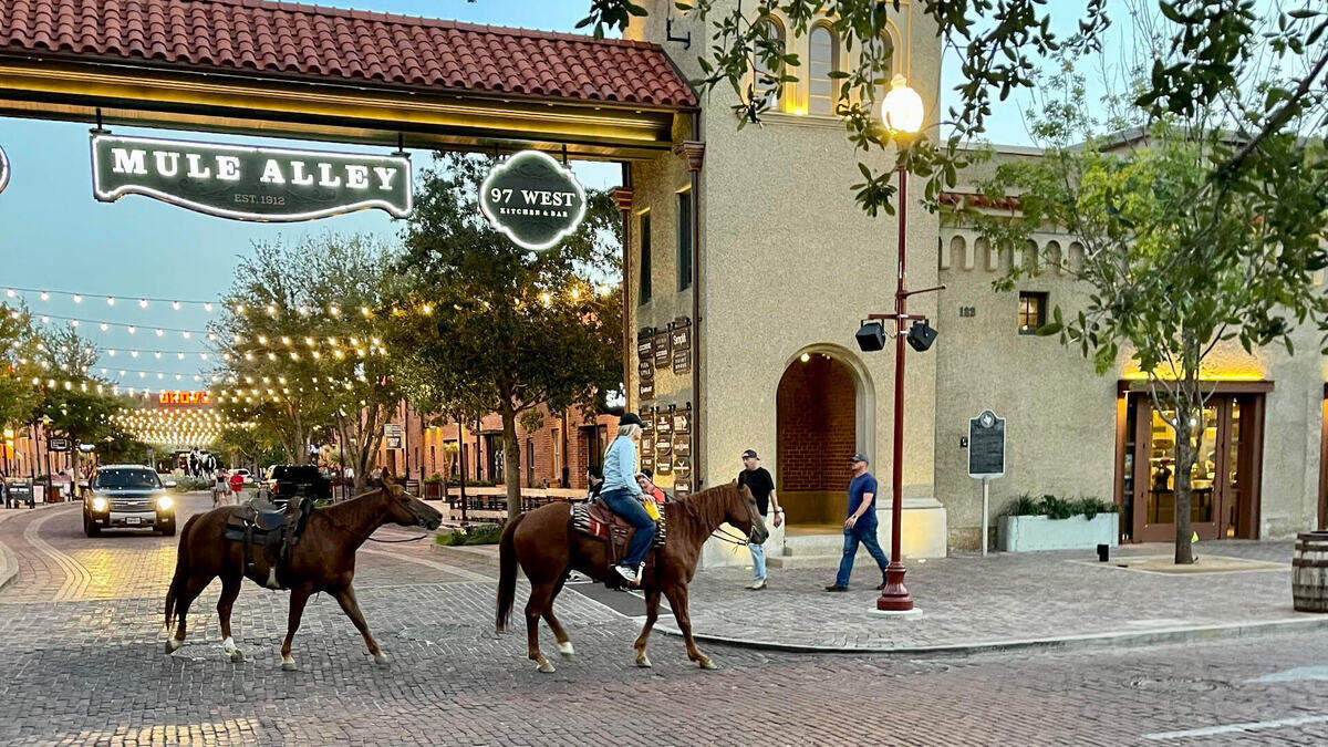 A pair of horses pass the entrance to Mule Alley in the Fort Worth Stockyards on Sept. 8, 2022.