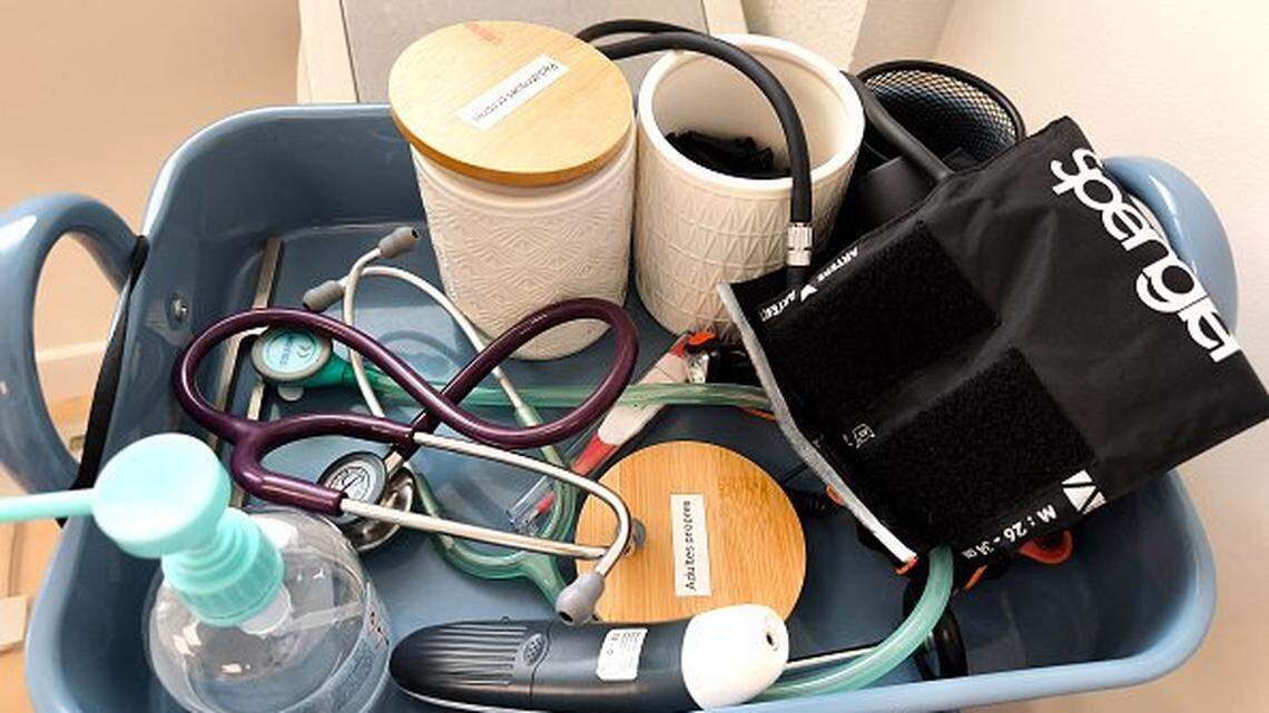 Medical instruments, a stethoscope, a thermometer and a blood pressure monitor on a trolley in a medical office.