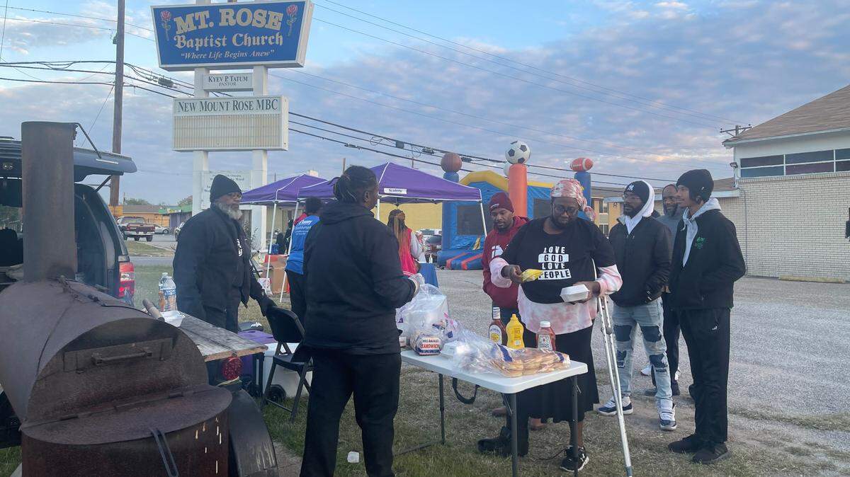 A groups of residents receive food in front of baptist church.