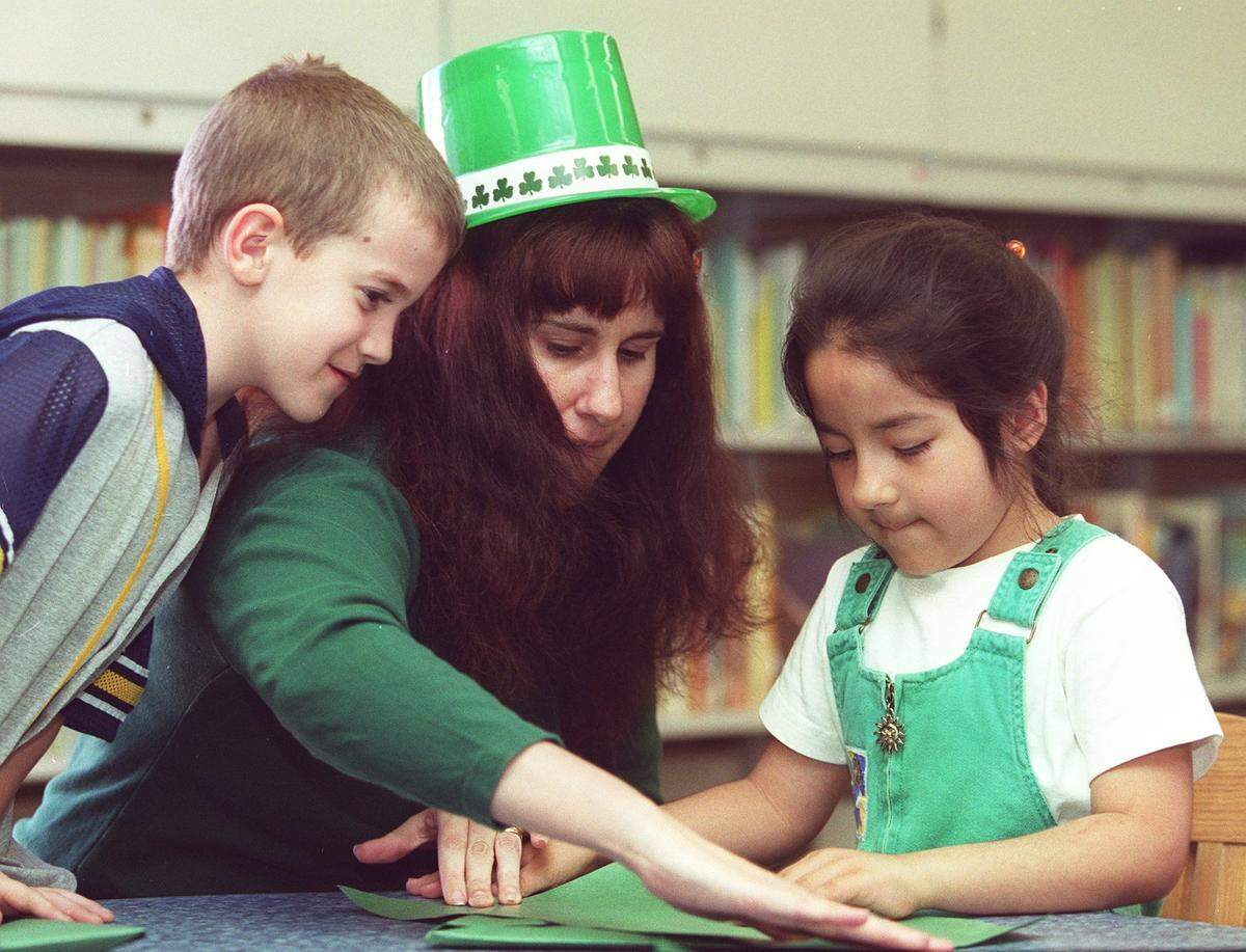 March 12, 2000: Taylor Collins, 8, of Fort Worth, and Natalie Rivas, 5, of North Richland Hills, are helped by library outreach assistant Allison Long to make St. Patrick’s Day hats at the Haltom City Library.