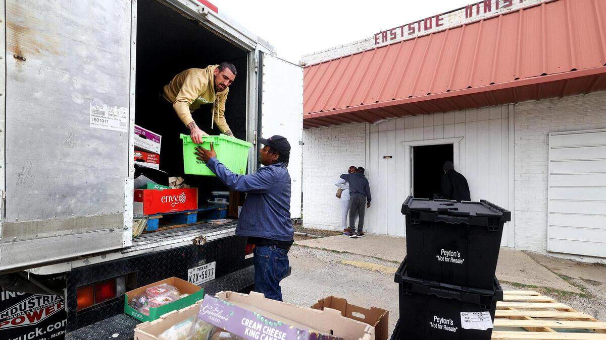William Gibbs, left, and Von Williams unload food from the back of a truck to be sorted and distributed those in need at Eastside Ministries on Friday in Fort Worth. The nonprofit was forced to convert to a drive-through method for food distribution after two fires in late November heavily damaged their food pantry area.