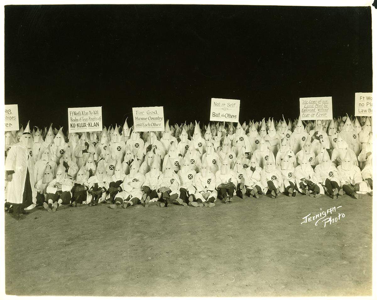 Ku Klux Klan gathering of the Fort Worth Klan No. 101; Klan members in robes and hoods holding signs, no date [ca. early 1920s].