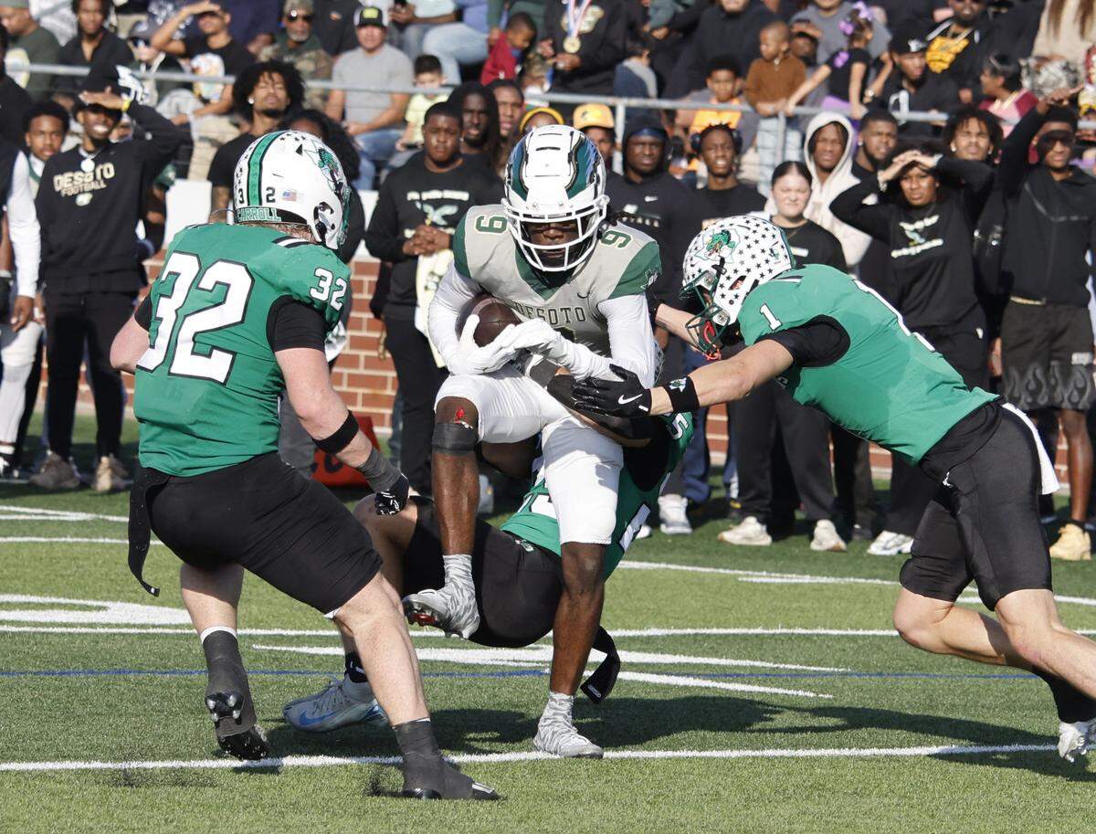 Southlake Carroll defensive backs Brock Boyd (1), Gavin Strange (25) linebacker William Leins (32) wrap up DeSoto wide receiver Antron Edmundson (9) after his catch during the first half of a UIL Class 6A Division II semifinal on Saturday Dec. 13, 2025 at Vernon Newsom Stadium in Mansfield, Texas.