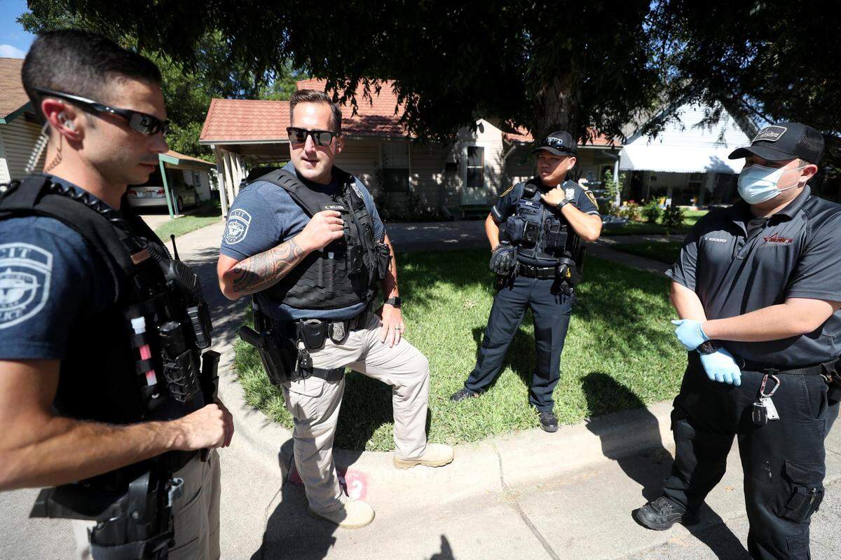 Fort Worth Police officers Cory Clackler, left, and Kyle Willcox, second from left, formulate a plan with patrol officers and MedStar while responding to a mental health call on August 11, 2021. Officers assigned to the team are not dispatched to calls, instead they respond to calls they feel have a mental health connection or when patrol officers request their help