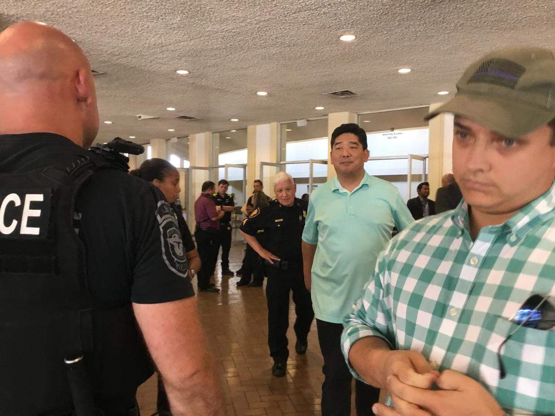 State Rep. Briscoe Cain, right, listens as local Republican judicial candidate Alex Kim discusses the incident with a Fort Worth police officer.