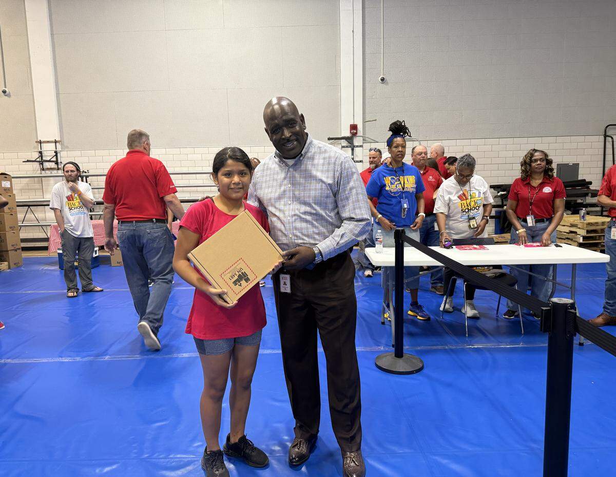 Erika Garcia, who will be starting grade 11, is receiving a new laptop from Rodney Hill, Sales Center Manager, Fossil Creek Arca Continental Coca-Cola Southwest Beverages.