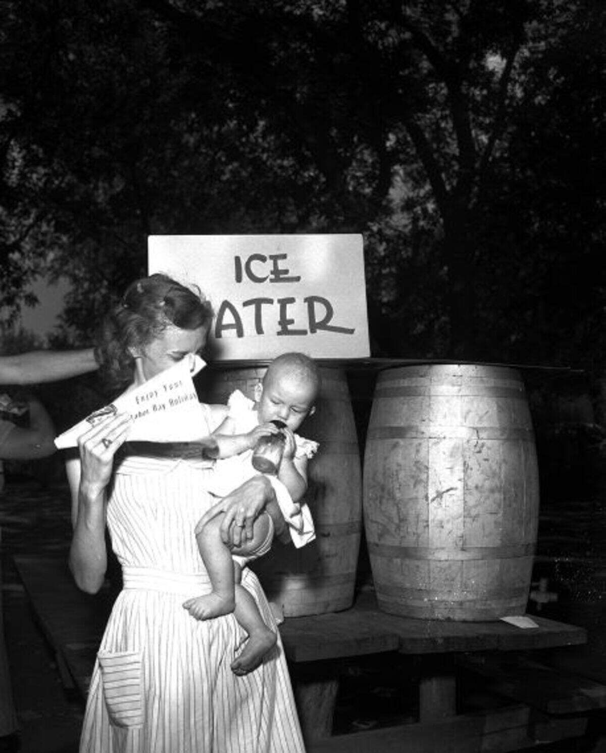 A woman is holding a baby and some kind of object in her left hand being pointed near the child.