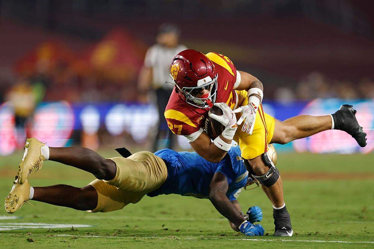 LOS ANGELES, CALIFORNIA - NOVEMBER 29: Riley Wormley #27 of the USC Trojans is hit by Andre Jordan Jr. #2 of the UCLA Bruins during the second quarter at Los Angeles Memorial Coliseum on November 29, 2025 in Los Angeles, California. (Photo by Harry How/Getty Images)