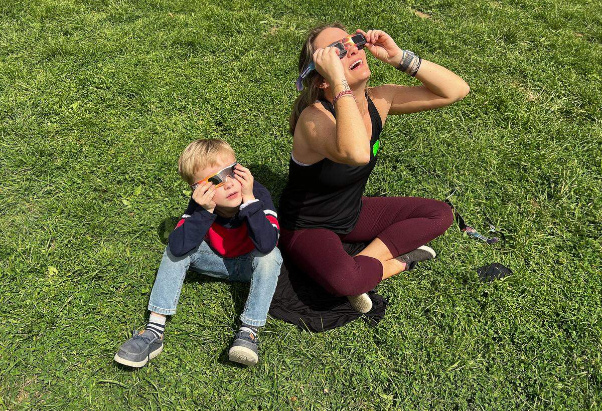 Kellen Egan, a kindergartener at Alice Carlson Applied Learning Center, stares at the sun with his mother Sara after watching the 2-minute totality on Monday, April 8, 2024. “When the clouds covered, it looked like a half moon. It looked like a ball of fire,” Kellen said.