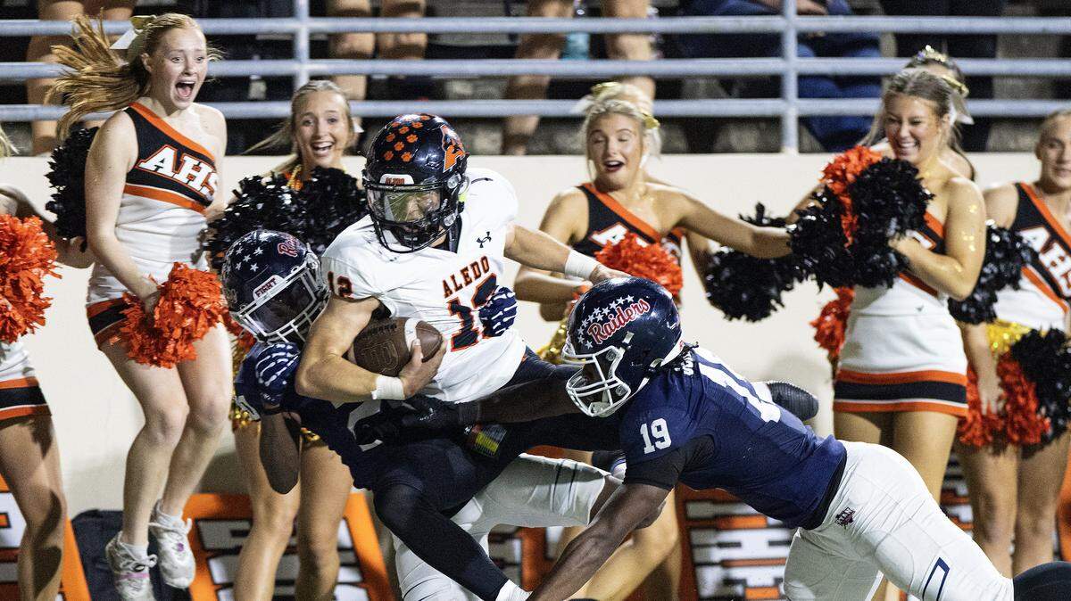 Aledo quarterback Lincoln Tubbs (12) gets tackled out of bounds into the cheerleaders in the second half of a high school football game between the Aledo Bearcats and the Denton Ryan Raiders at C.H. Collins Athletic Complex in Denton on Friday, Oct. 3, 2025.