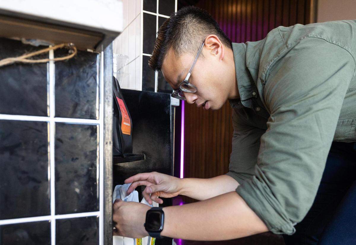 Toan Luong, Ampersand’s operating partner, fixes bags of coffee at the West 7th district location.