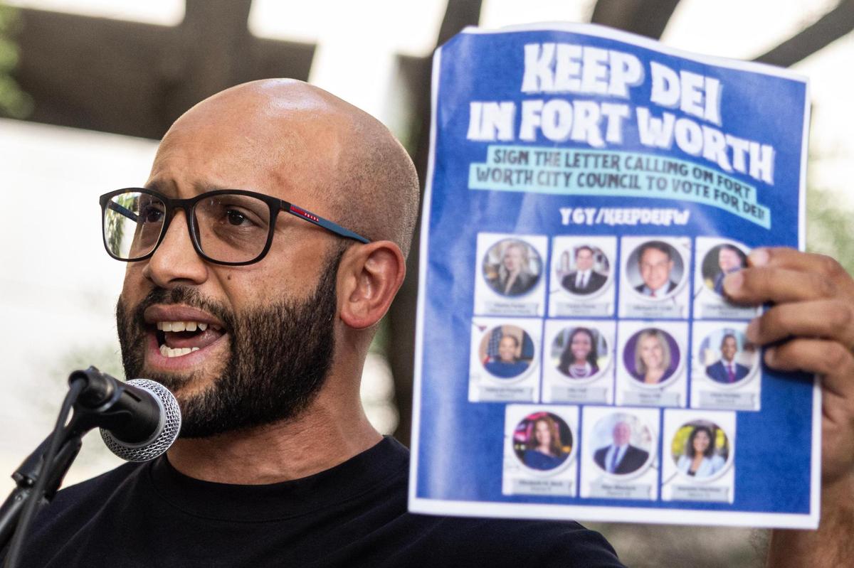 EJ Carrion holds a flyer saying “Keep DEI in Fort Worth” while speaking to a crowd gathered for the ‘Good Trouble’ rally in Burk Burnett Park in downtown Fort Worth on Thursday, July 17, 2025.