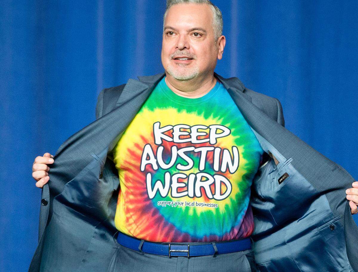 DNC Finance Chairman Henry Munoz, opens up his suit jacket to reveal his ‘Keep Austin Weird’ tie-dye t-shirt, on stage before introducing President Barack Obama at DNC fundraiser at the Austin Music Hall in Austin, Texas, Friday, March 11, 2016.