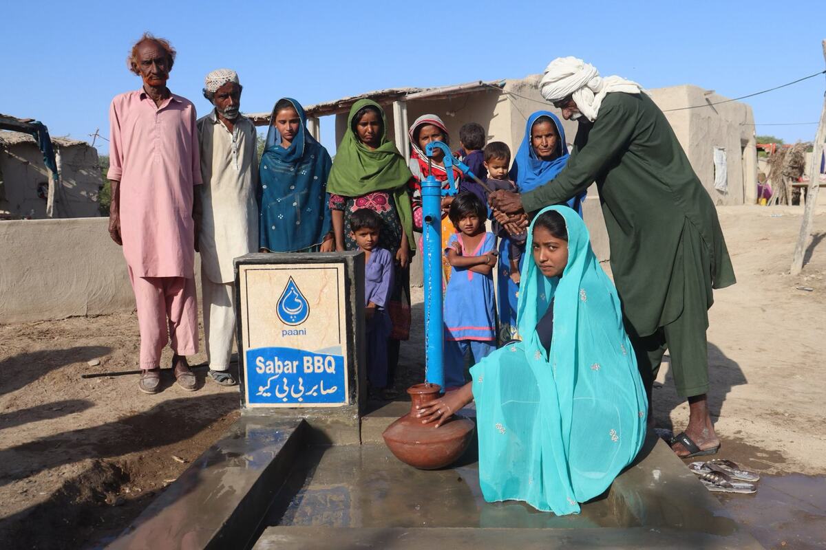 A photo of the Abdulrahaman family in the Mohammed Khan vadhoMon village in Pakistan next to a well built from the Paani Project due to a donation from Zain Shafi and Sabar BBQ in March 2024. Shafi donates his profits to Paani, a nonprofit that delivers clean water to areas in Pakistan in need.