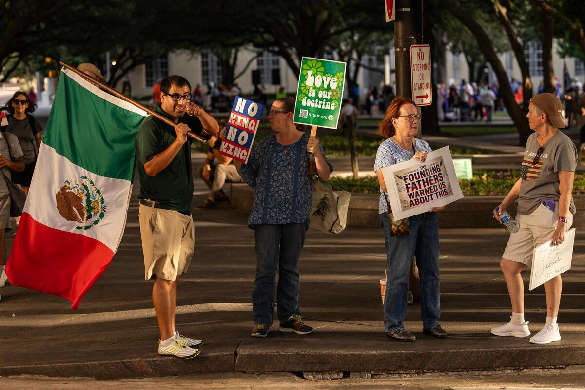 Rally attendees holds signs on the sidewalk during the ‘Good Trouble’ rally in Burk Burnett Park in downtown Fort Worth on Thursday, July 17, 2025.