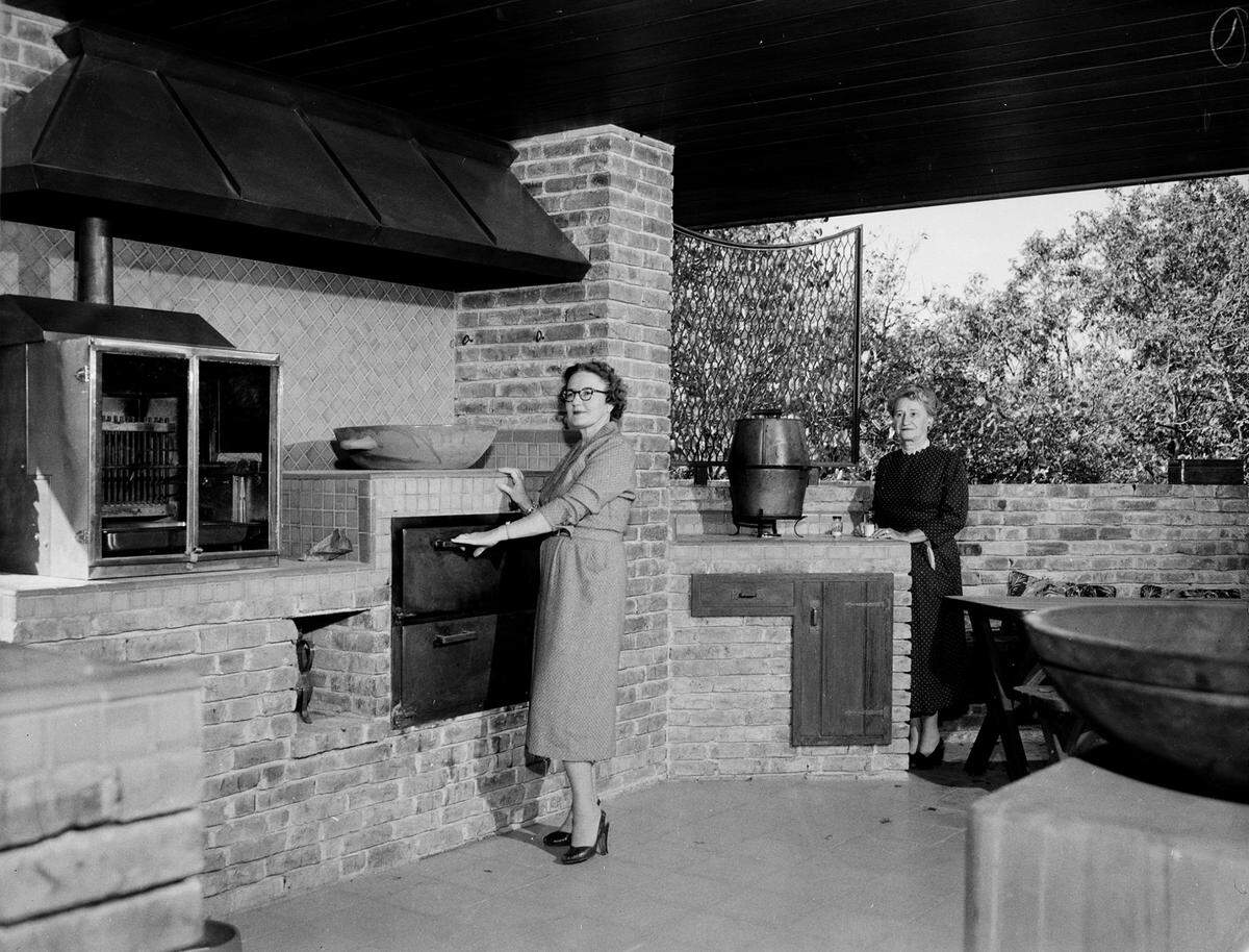 April 5, 1955: Mrs. Charles Little and Mrs. Alfred McKnight in the outdoor kitchen of Julian Meeker, 309 Crestwood Drive, Fort Worth.