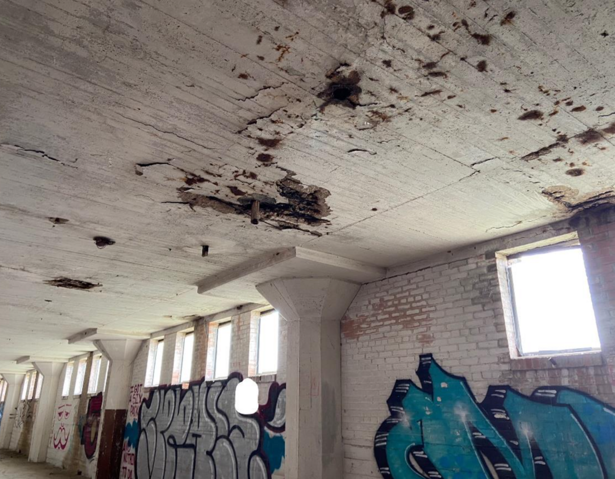 The sixth floor of the T&P Warehouse displays graffiti and various areas of spalled concrete.