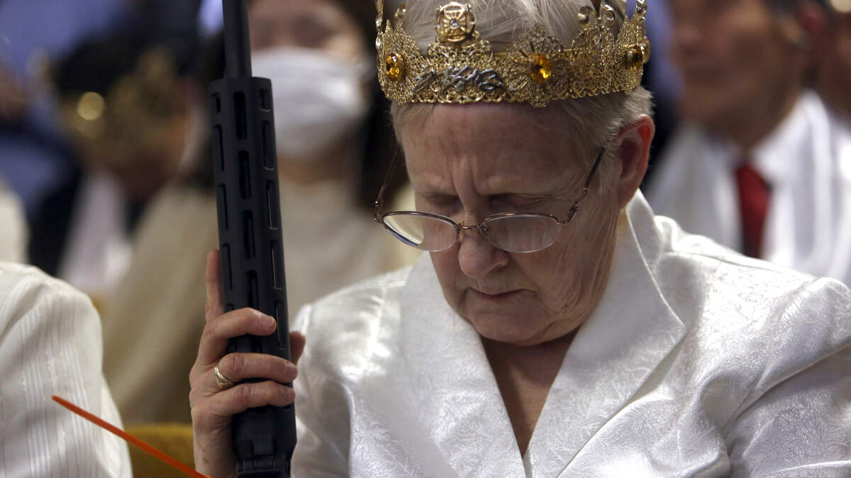 A woman wears a crown and holds an unloaded weapon as she bows her head during services at the World Peace and Unification Sanctuary, Wednesday Feb. 28, 2018 in Newfoundland, Pa. Worshippers clutching AR-15 rifles participated in a commitment ceremony at the Pennsylvania-based church.The event Wednesday morning led a nearby school to cancel classes for the day.The church’s leader, the Rev. Sean Moon, said in a prayer that God gave people the right to bear arms. (AP Photo/Jacqueline Larma)
