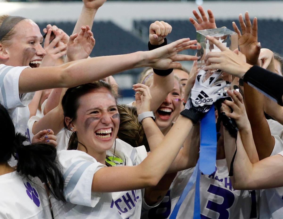The Paschal Lady Panthers reach in to touch the trophy after a Fort Worth ISD flag football game at ATT Stadium in Arlington, Texas, Wednesday, May 18, 2022. Paschal defeated Carter Riverside 33-13. (Special to the Star-Telegram Bob Booth)