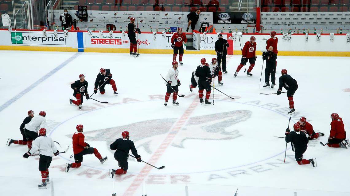 Arizona Coyotes players and coaches pause on the ice during NHL hockey practice at Gila River Arena, Monday, July 13, 2020, in Glendale, Ariz. (AP Photo/Ross D. Franklin)
