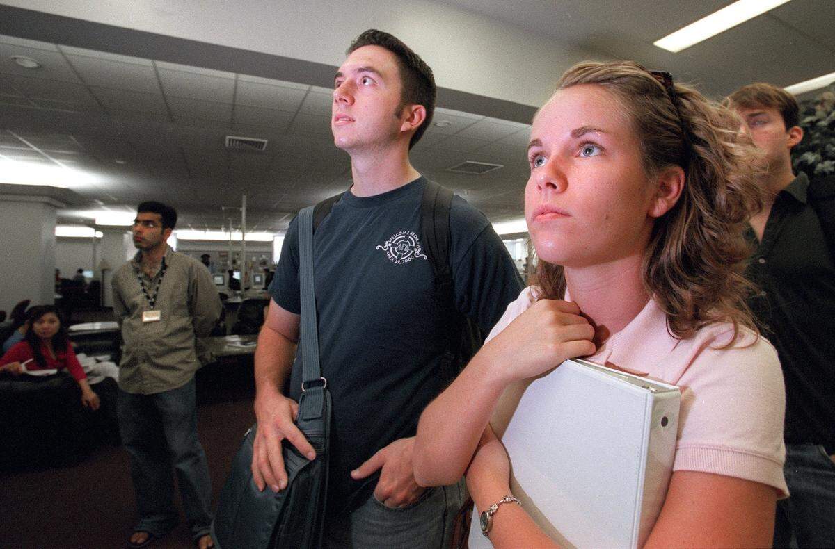 UTA’s Rick Underbrink and Jessica Harris watch in silence the broadcast of a commercial plane that crashed into the World Trade Center on Sept. 11, 2001.