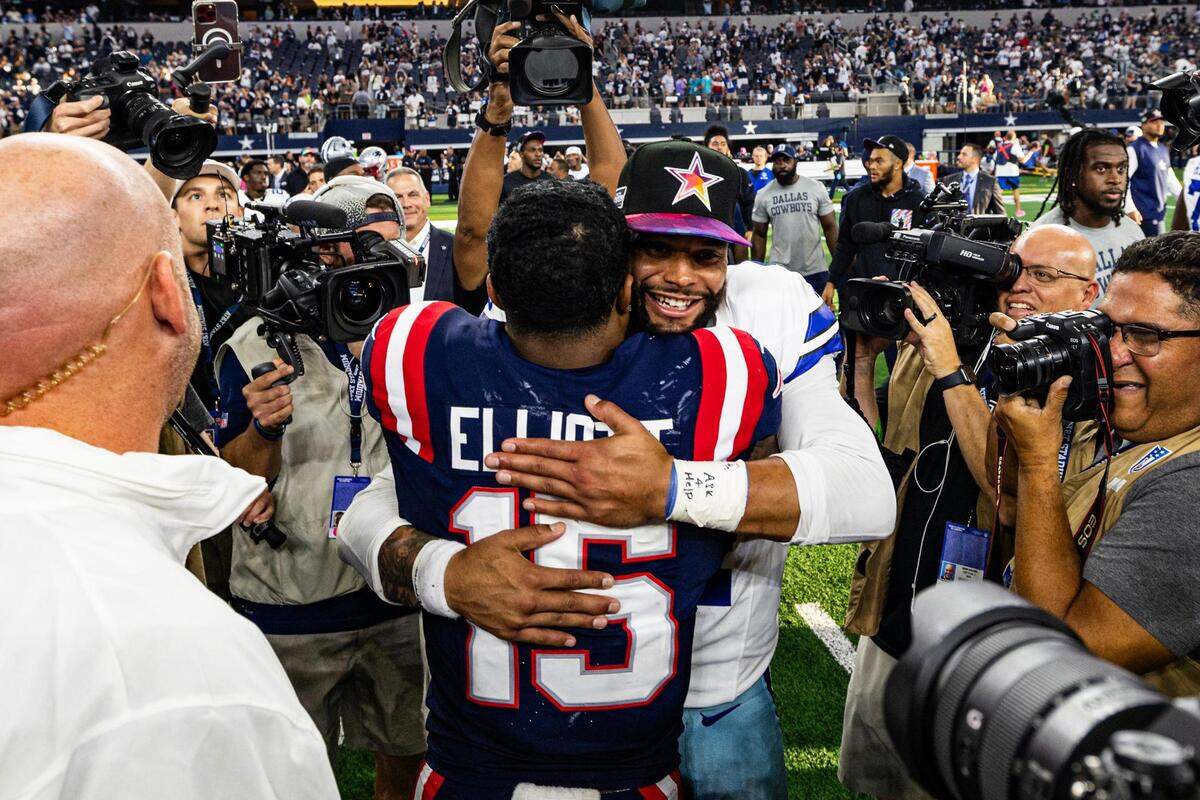 Former teammates Ezekiel Elliot (15) and Dak Prescott (4) embrace after an NFL game between the Dallas Cowboys and New England Patriots at AT&T Stadium in Arlington on Sunday, Oct. 1, 2023. The Cowboys won 38-3 in their reunion.