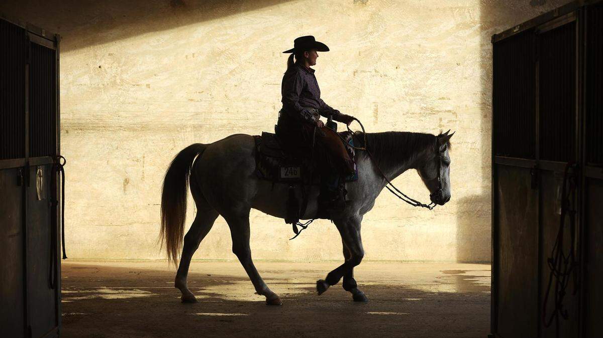 Ally Hurt and quarter horse Lous Rusty Handle are silhouetted as they leave the barn during the first day of a Texas rodeo on Friday, January 14, 2021.
