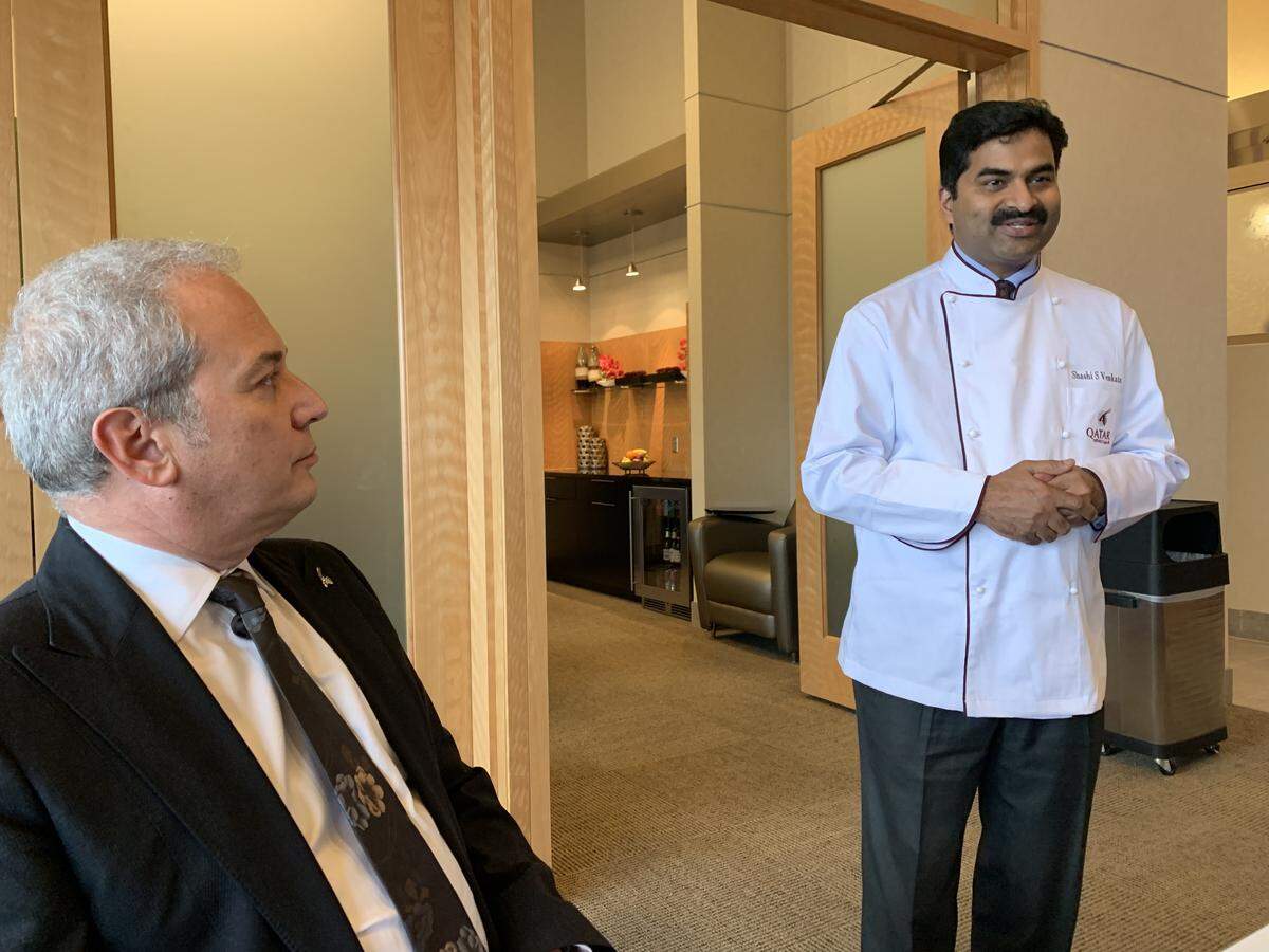 Eric Odone (left), Qatar Airways senior vice president for the Americas, listens as the airline’s chef, Shashi Venkata, explains the types of food offered in Qsuite business class