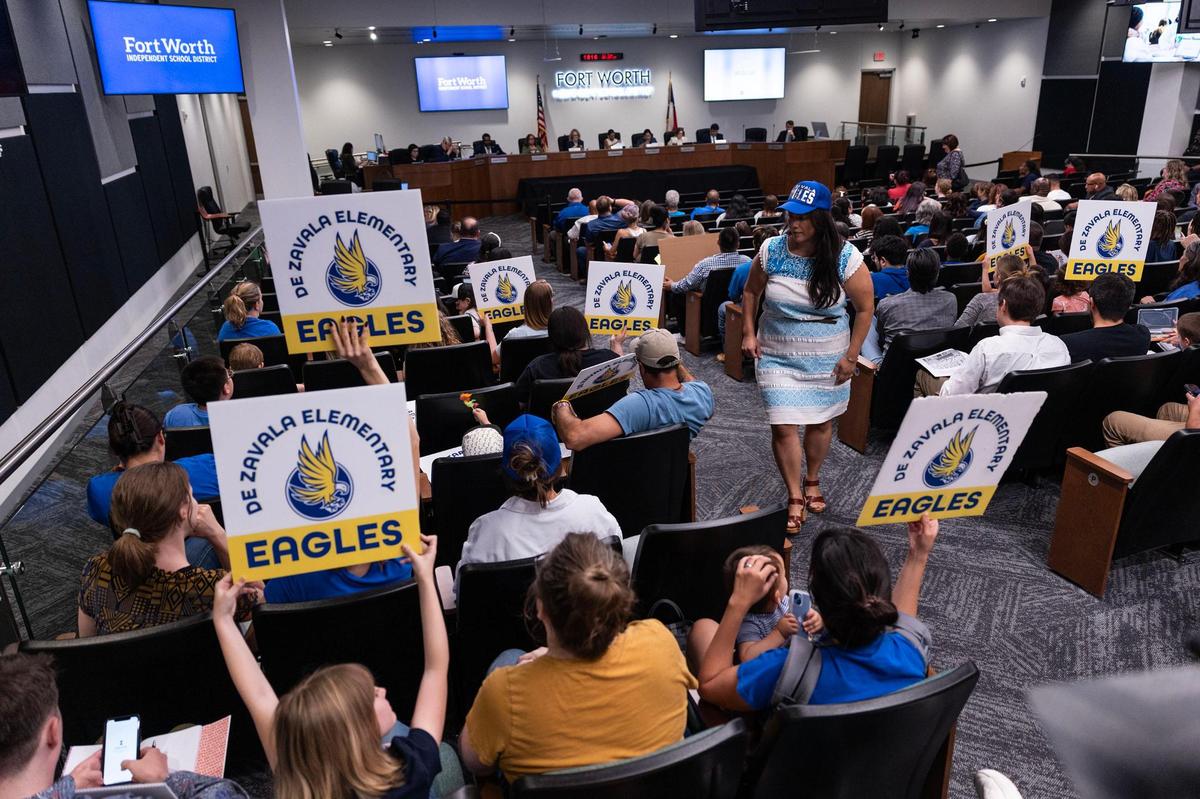 Parents and students in support of keeping De Zavala Elementary open hold signs during a Fort Worth ISD School Board meeting on May 20.