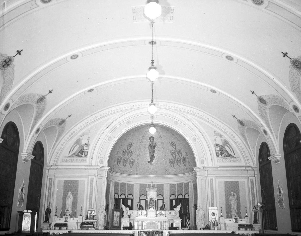 Interior of Saint Mary's Catholic Church, 509 W. Magnolia Ave. The church has a barrel vault ceiling, with hanging-globe lights, decorations of religious statues and paintings. There are medallions seen above the stained glass windows.